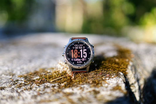 Garmin Fenix GPS watch resting on moss-covered stone in natural light, essential trail running gear for Hudson Valley trails